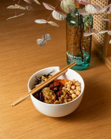 Bowl of mixed grains and vegetables with chopsticks on a wooden table.